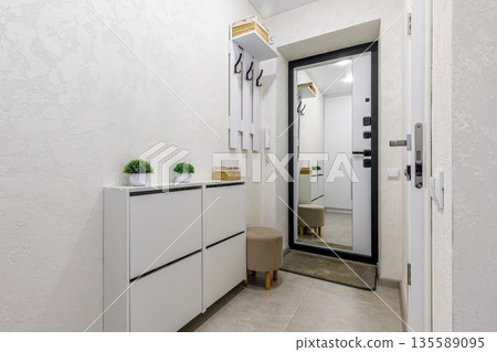 Bright minimalist entryway interior with white shoe cabinet and mirror Bright minimalist entryway interior with white shoe cabinet and mirror 135589095