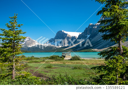 Wooden footbridge on Bow Lake's lakeside walkway with mountains in the background, Alberta, Canada 135589121