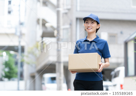 Middle-aged female delivery person delivering packages by car 135589165