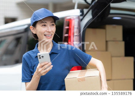 Middle-aged female delivery person delivering packages by car 135589176