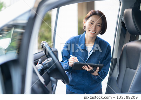 Middle-aged female auto mechanic repairing a car 135589209