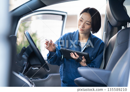 Middle-aged female auto mechanic repairing a car Middle-aged female auto mechanic repairing a car 135589210