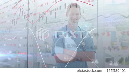 Standing doctor wearing scrubs with stethoscope folding arms at clinic with glass panels and charts 135589401