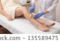 Woman receives leg hair removal treatment at a beauty salon during daytime 135589475