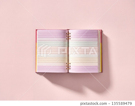 Open notebook with lined pages lying on a pink background created for note-taking or journaling in a study space 135589479