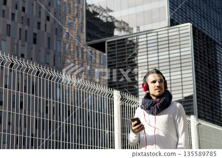 Caucasian man listening to music with smartphone outdoors Caucasian man listening to music with smartphone outdoors 135589785