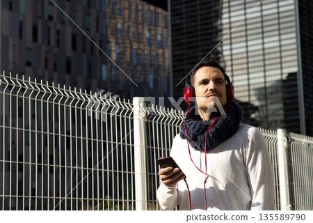 Caucasian man listening to music with smartphone outdoors Caucasian man listening to music with smartphone outdoors 135589790