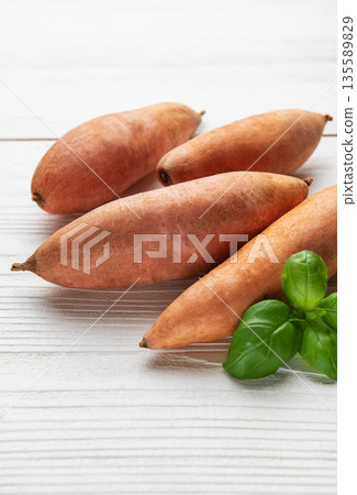 Sweet potatoes and basil on white wood background 135589829