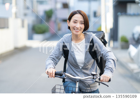 A woman delivering food by bicycle 135590109