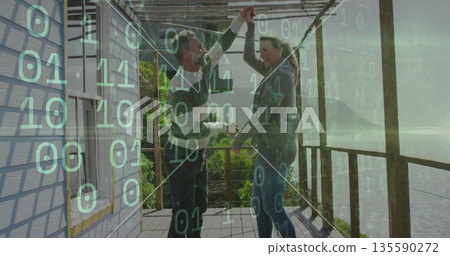 Dancing couple holding hands under pergola beams on wooden deck, green binary code overlay Dancing couple holding hands under pergola beams on wooden deck, green binary code overlay 135590272