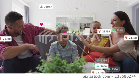 Sitting family on grey sofa in bright living room, being surrounded by floating notification icons Sitting family on grey sofa in bright living room, being surrounded by floating notification icons 135590274