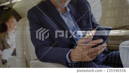 Tapping bearded executive man in suit using tablet in aircraft cabin, with encryption overlays 135590356