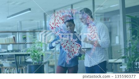 Collaborating colleagues examining tablet computer projecting holographic globe in open-plan office 135590377