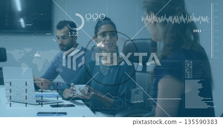 Collaborating, three colleagues examining data overlays in conference room, with laptop, coffee mug 135590383