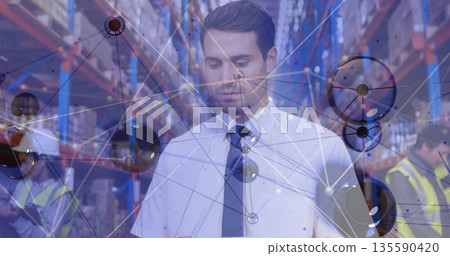 Viewing network overlay on tablet, man in white shirt, dark tie standing amid warehouse aisle Viewing network overlay on tablet, man in white shirt, dark tie standing amid warehouse aisle 135590420