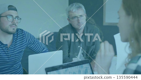 Leading silver-haired dark-shirted man reviewing charts in meeting room with laptops and documents Leading silver-haired dark-shirted man reviewing charts in meeting room with laptops and documents 135590444
