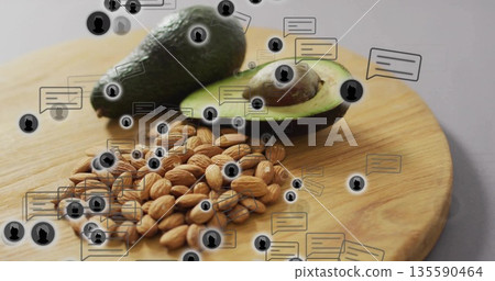 Displaying halved avocado, whole avocado, almonds on cutting board on table, with floating icons Displaying halved avocado, whole avocado, almonds on cutting board on table, with floating icons 135590464