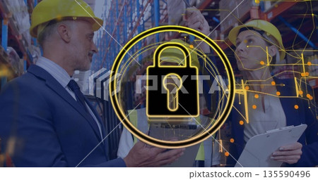 Warehouse professionals wearing helmets auditing security in warehouse aisle, with padlock, tablet Warehouse professionals wearing helmets auditing security in warehouse aisle, with padlock, tablet 135590496