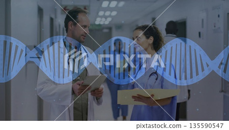 Doctor and nurse holding folder discussing study reviewing tablet in hospital hall, with DNA 135590547