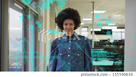 Woman wearing denim jacket viewing holographic data in office corridor, hexagon molecular graphics Woman wearing denim jacket viewing holographic data in office corridor, hexagon molecular graphics 135590639