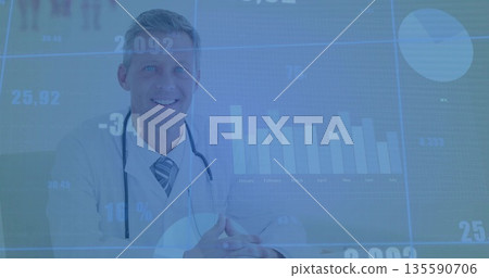 Doctor wearing white coat and tie reviewing digital charts at desk in clinic, with stethoscope 135590706