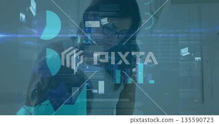 Analyzing businesswoman interacting with digital charts and holographic interface in modern office 135590723