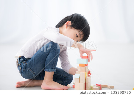 一個男孩正在興致勃勃地玩積木。耶,我做到了!這張圖展現了智力挑戰和非認知能力。 一個男孩正在興致勃勃地玩積木。耶,我做到了!這張圖展現了智力挑戰和非認知能力。 135590750
