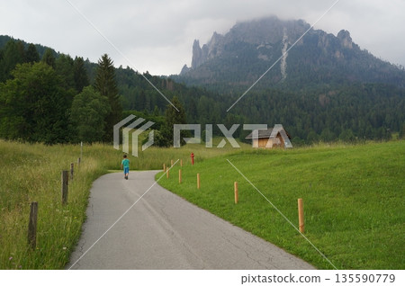 Child Walking on Mountain Road in Scenic Landscape 135590779