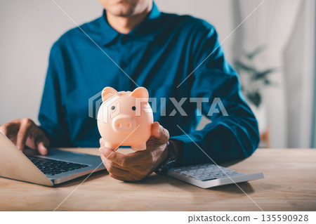 Man holds piggy bank car bank learning e education financial online money elearning internet, using laptop and calculator to manage monthly costs for professional study course plan Man holds piggy bank car bank learning e education financial online money elearning internet, using laptop and calculator to manage monthly costs for professional study course plan 135590928