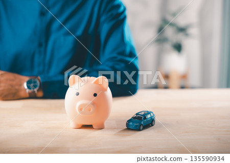 Car money bank insurance piggy save auto loan cost finance fuel saving tax, person manages budget for vehicle purchase, using toy car and piggy bank as financial symbols for saving 135590934