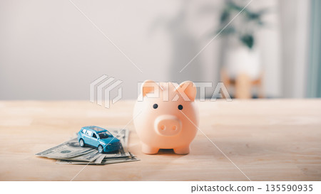 Piggy bank money car gdp savings insurance finance health budget save, blue toy vehicle on dollar bills represents automotive growth or financial investment strategy plan concept Piggy bank money car gdp savings insurance finance health budget save, blue toy vehicle on dollar bills represents automotive growth or financial investment strategy plan concept 135590935
