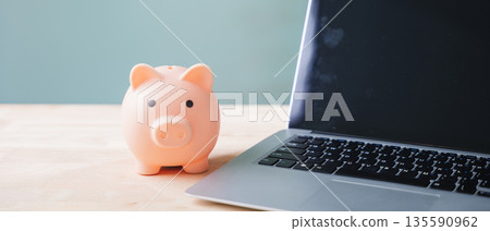Piggy bank for money financial online learning e education elearning internet goals sits beside laptop on wooden table, helping students save for remote university courses Piggy bank for money financial online learning e education elearning internet goals sits beside laptop on wooden table, helping students save for remote university courses 135590962