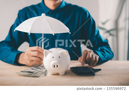 Piggy bank money protect financial insurance concept risk umbrella and finance collage shows man using calculator with cash to manage wealth safety and secure future savings Piggy bank money protect financial insurance concept risk umbrella and finance collage shows man using calculator with cash to manage wealth safety and secure future savings 135590972