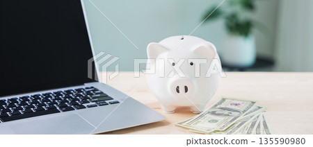 piggy bank online money elearning internet financial e learning education budget goals involve saving for courses beside laptop computer with cash on wooden surface in office piggy bank online money elearning internet financial e learning education budget goals involve saving for courses beside laptop computer with cash on wooden surface in office 135590980