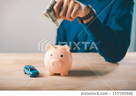 Saving money in piggy bank to save for car insurance and fuel cost, managing gas price or auto finance and tax while building saving for future travel budget and trip expenses Saving money in piggy bank to save for car insurance and fuel cost, managing gas price or auto finance and tax while building saving for future travel budget and trip expenses 135590986