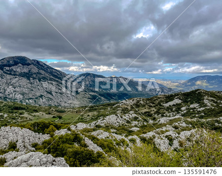 The breathtaking mountain landscape is beautifully set against a dramatic sky filled with clouds 135591476