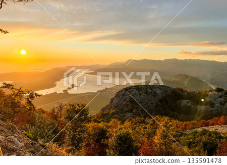 Witness the breathtaking beauty of a spectacular sunset over a serene river and majestic mountains Witness the breathtaking beauty of a spectacular sunset over a serene river and majestic mountains 135591478