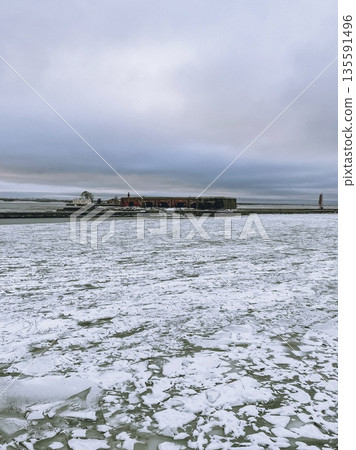 Frozen Landscape Featuring Icy Terrain and a Dramatic Cloudy Sky Above the Horizon Frozen Landscape Featuring Icy Terrain and a Dramatic Cloudy Sky Above the Horizon 135591496