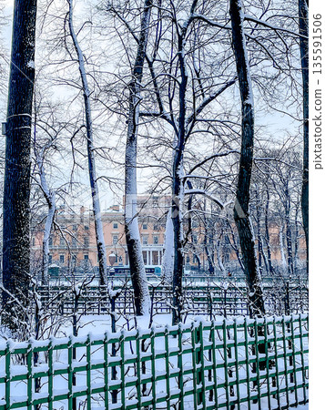 A Beautiful Snowy Winter Scene Depicting Trees and a Charming Fence in an Urban Environment 135591506