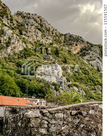 The remarkable ancient ruins nestled on a breathtaking mountainside surrounded by lush greenery The remarkable ancient ruins nestled on a breathtaking mountainside surrounded by lush greenery 135591507