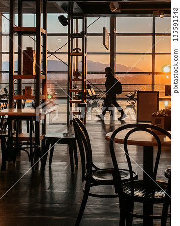 A Beautiful Silhouette of a Person Taking a Leisurely Stroll Through a Sunset Cafe A Beautiful Silhouette of a Person Taking a Leisurely Stroll Through a Sunset Cafe 135591548