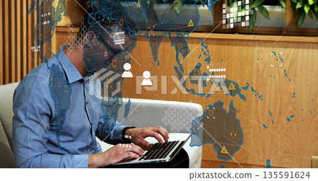 Sitting man wearing eyeglasses, light-blue shirt typing on laptop on sofa in office lounge Sitting man wearing eyeglasses, light-blue shirt typing on laptop on sofa in office lounge 135591624