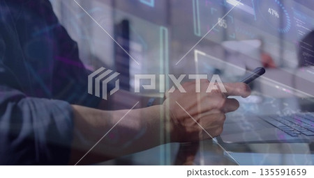 Analyzing digital overlays on laptop and holding smartphone, worker wearing shirt in modern office 135591659