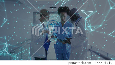 Staff wearing medical attire reviewing data in hospital hall with tablet, clipboard and stethoscope Staff wearing medical attire reviewing data in hospital hall with tablet, clipboard and stethoscope 135591719