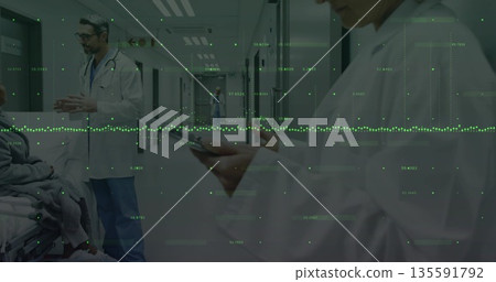 Checking mature nurse viewing smartphone device in hospital corridor, with gurney and medical staff 135591792