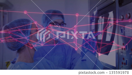 Medical doctors in scrubs masks gloves viewing X-ray on screen in hospital lab with pink overlay Medical doctors in scrubs masks gloves viewing X-ray on screen in hospital lab with pink overlay 135591978
