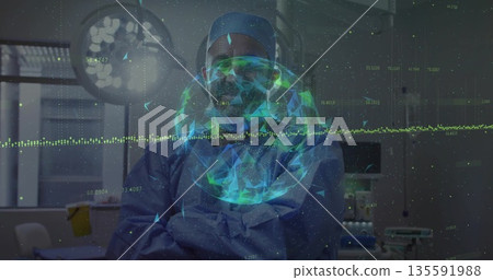 Standing surgeon wearing blue scrubs and goggles in operating room with monitors and hologram globe 135591988