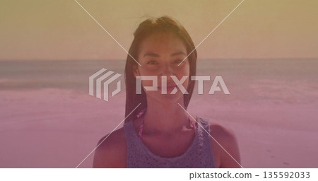 Posing woman wearing blue crochet tank top over pink bikini at beach shore, with sunset sky Posing woman wearing blue crochet tank top over pink bikini at beach shore, with sunset sky 135592033