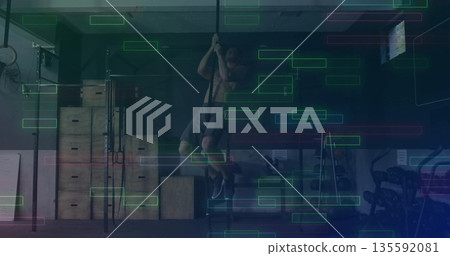 Climbing shirtless man ascending thick rope in fitness gym, with plyo boxes squat rack barbells Climbing shirtless man ascending thick rope in fitness gym, with plyo boxes squat rack barbells 135592081