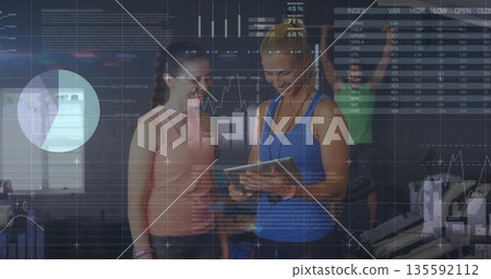 Analyzing tablet data instructor and client working at gym displaying digital overlays and machines Analyzing tablet data instructor and client working at gym displaying digital overlays and machines 135592112